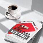 Show Your Red Card: Send Negativity Packing by A.L. Nicholson – a paperback Christian book resting on a white table beside a cup of coffee.